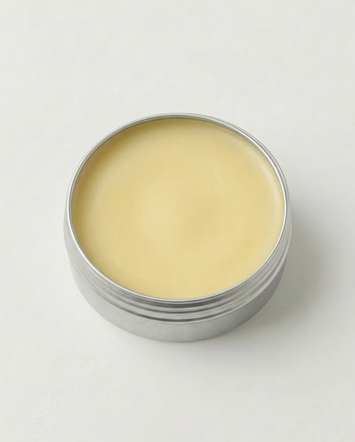 Metal container with beige cream on a white background