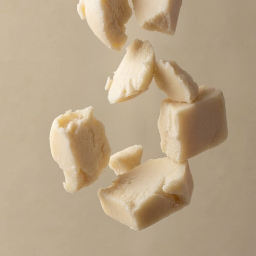 Chunks of beef tallow falling against a beige background