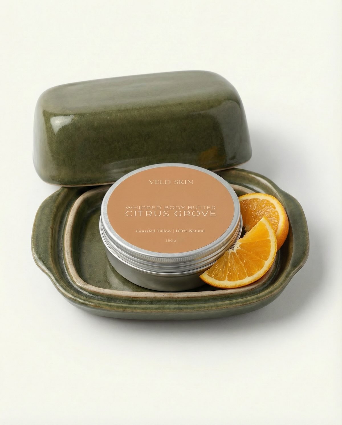 Body butter in a green container with oranges on a white background