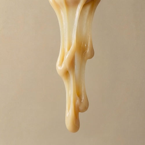 Close-up of lanolin being dripped against a beige background