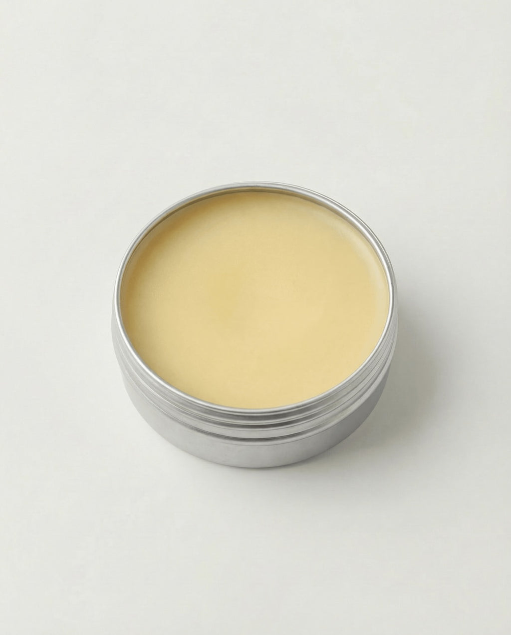 Silver tin with beige cream on a white background