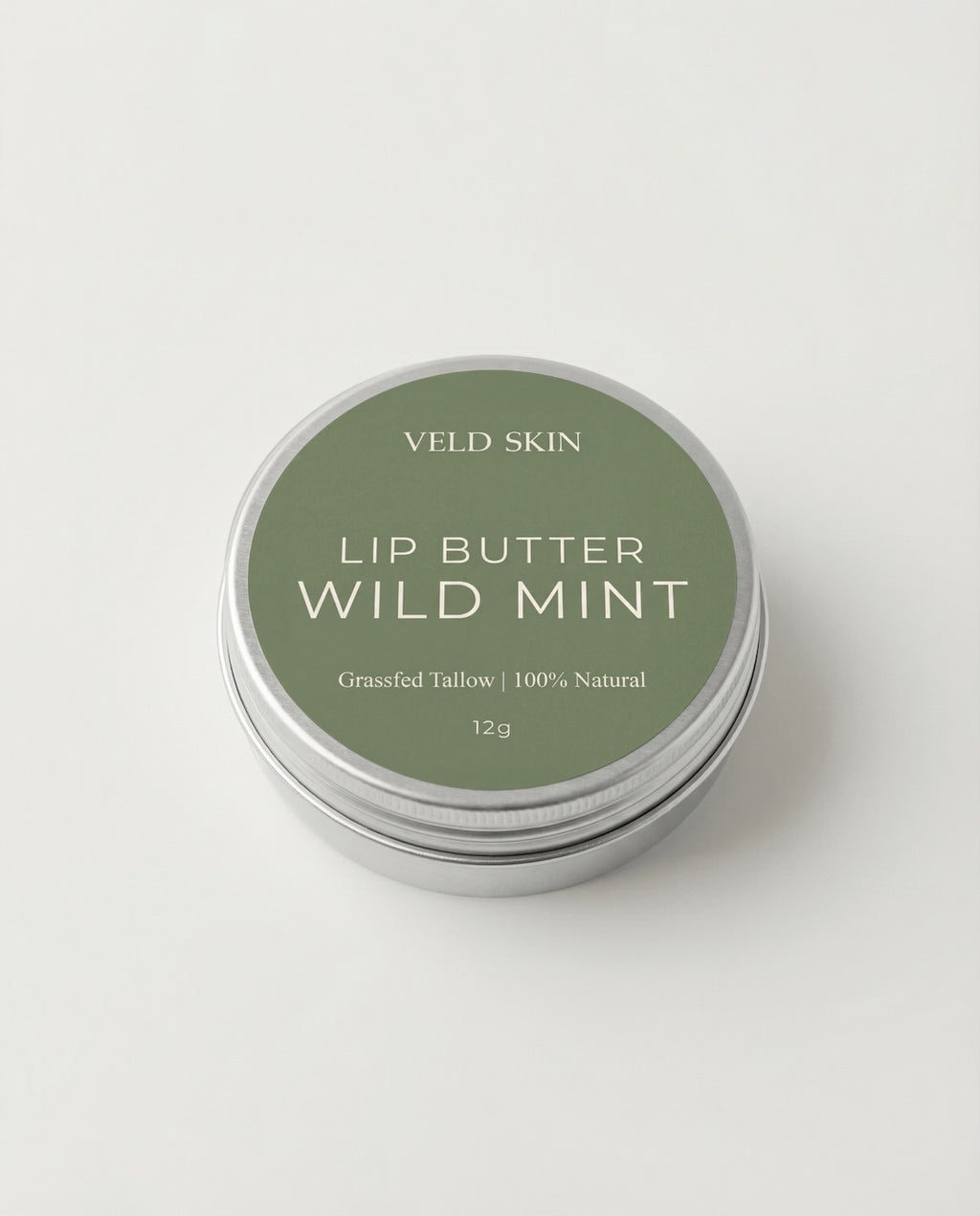 Lip butter container labeled 'Wild Mint' by Veld Skin on a light gray background