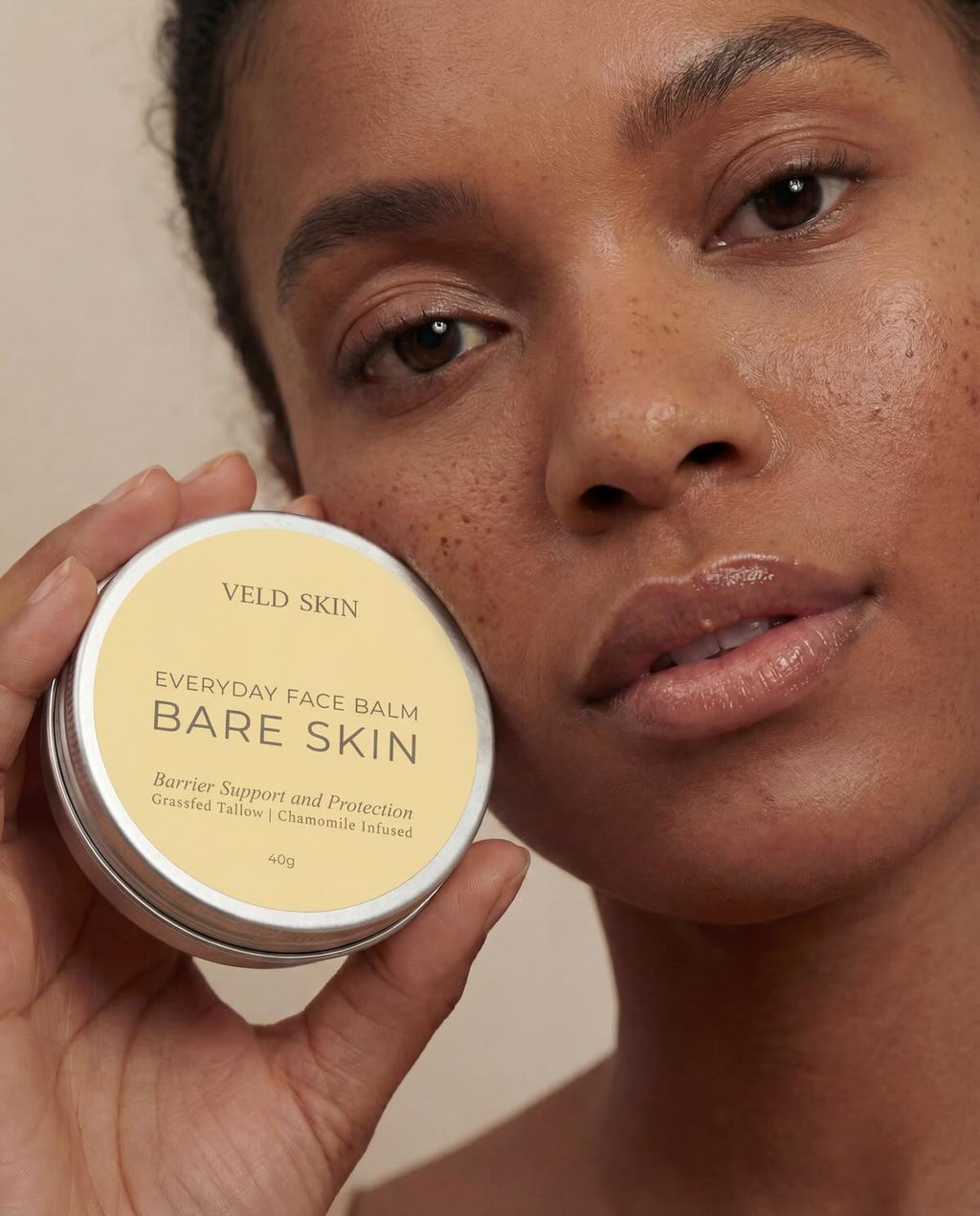 Person holding a container of Veld Skin Everyday Face Balm Bare Skin against a neutral background