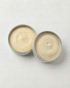 Two open tins of cream on a light gray background