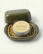 Balm container labeled 'Bare Skin' with a lid open on a white background