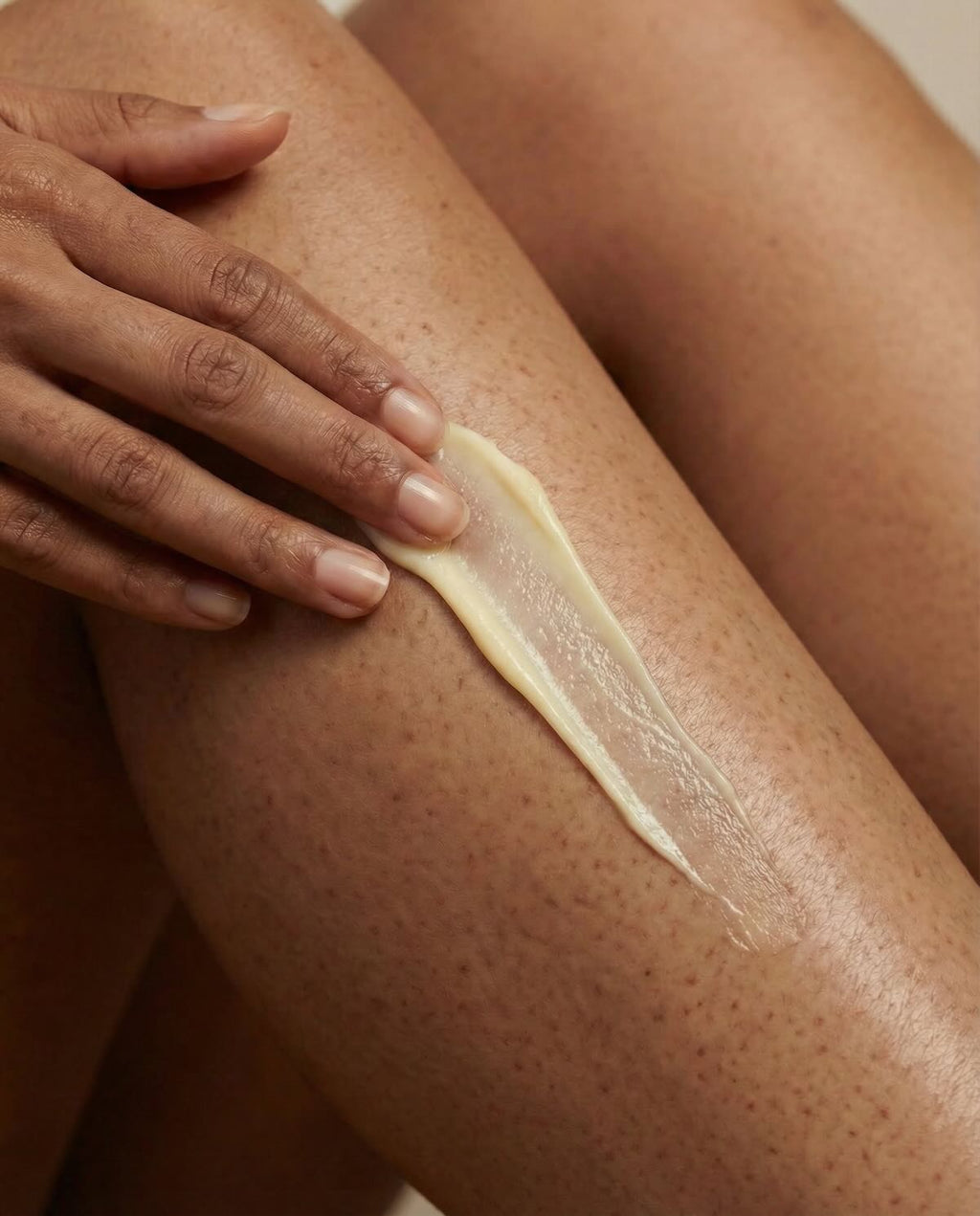 Hand applying a white cream or lotion to a leg