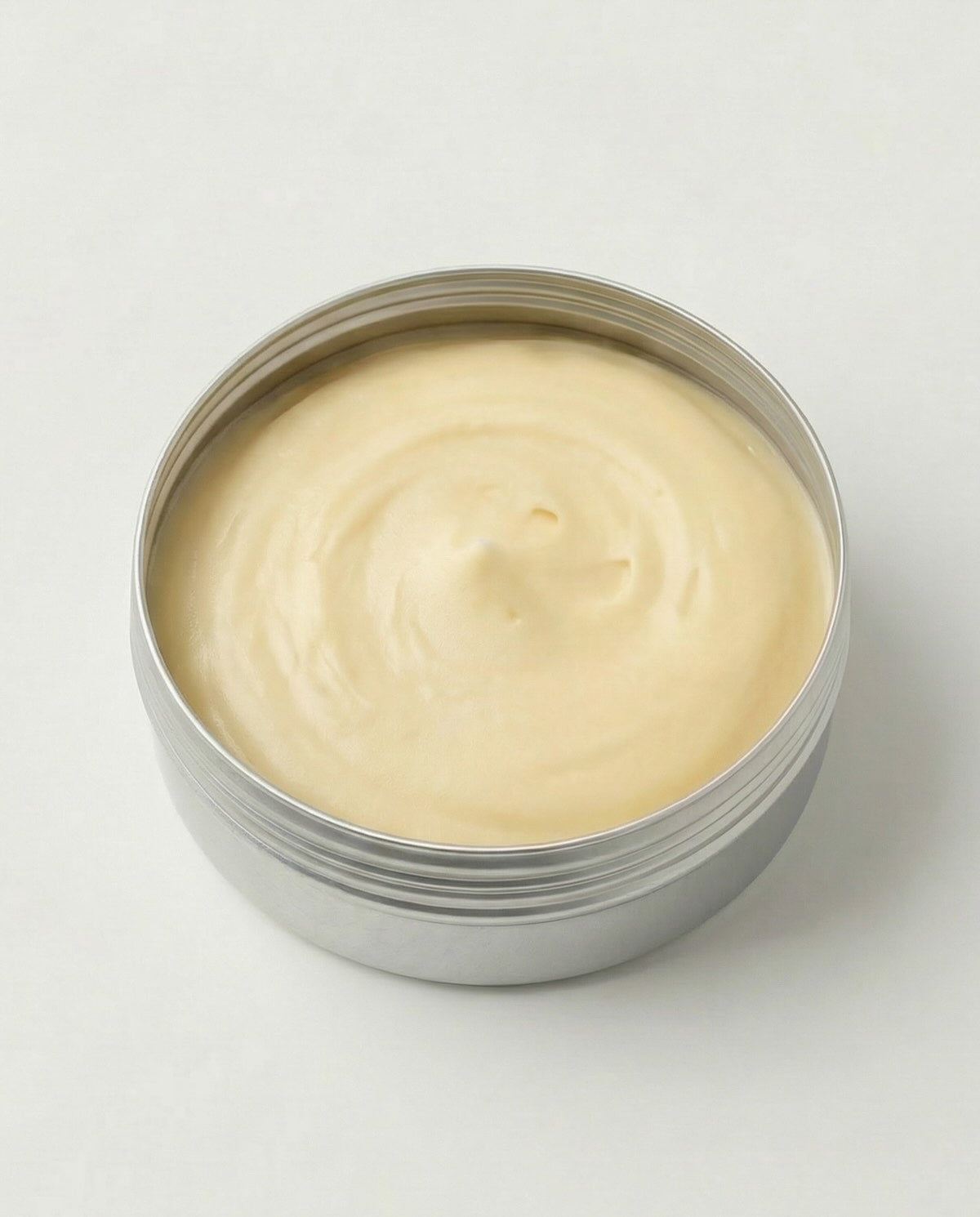 Metal container with creamy beige substance on a light gray background