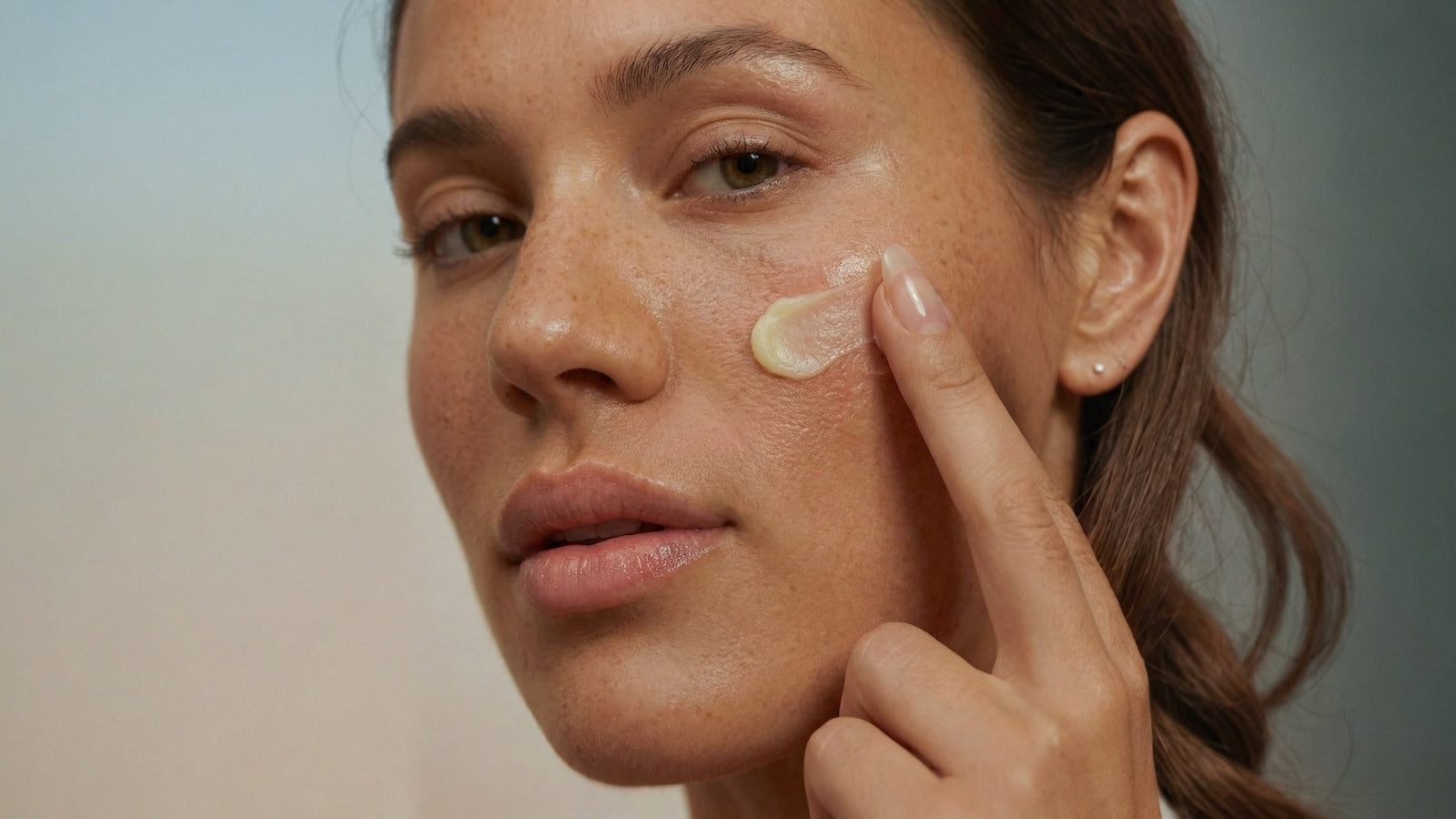 Woman applying cream to her face with a blurred background