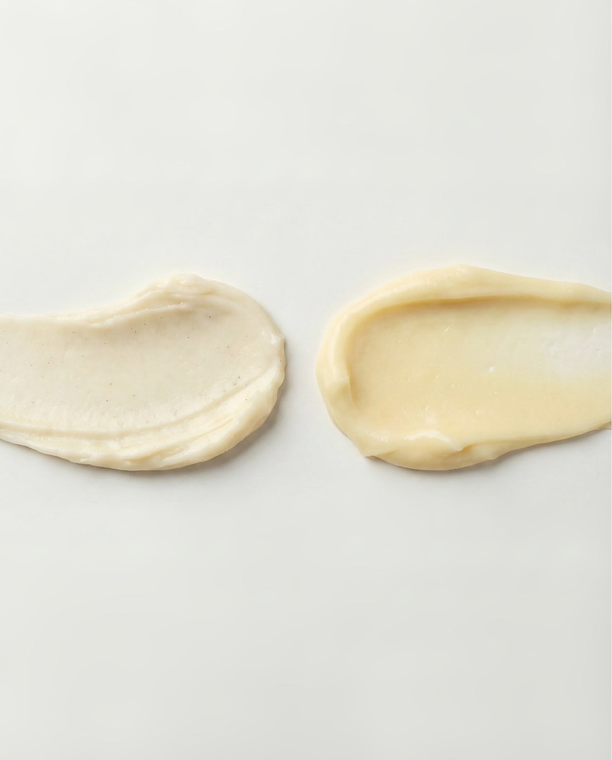 Two smears of cream on a light gray background