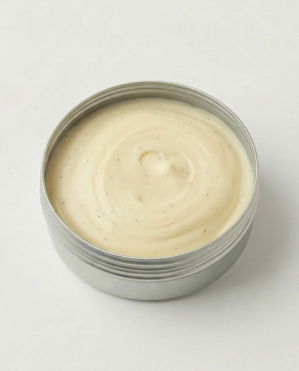 Metal container with creamy white substance on a light gray background