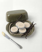 Set of vanilla butter tins with a wooden spreader on a white background